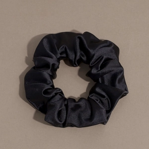 Close-up detail of smooth black satin fabric texture on a large elastic hair scrunchie