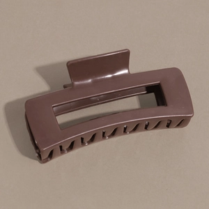 Gros plan sur la pince à cheveux rectangulaire marron foncé mat au design creux