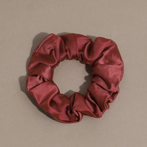 Close-up of wine red satin scrunchie with soft twill texture and elastic ring design