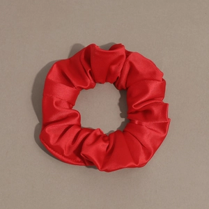 Macro shot of a classic bright red satin scrunchie showing detailed silk texture and folds