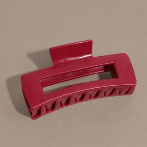 Vue macro d'une pince à cheveux rectangulaire rouge au design géométrique creux et fini mat