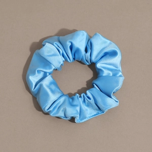 Detail of a shiny blue satin scrunchie with soft pleated texture and strong elasticity