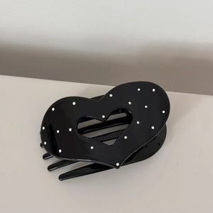 Detail shot of black heart-shaped hair claw clip with white polka dots and glossy finish