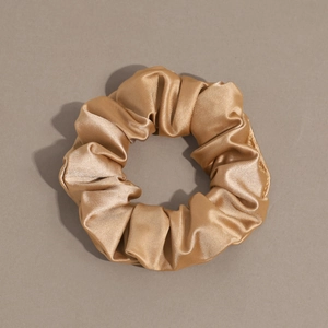 Detailed view of large champagne gold satin silk scrunchie with smooth pleated texture