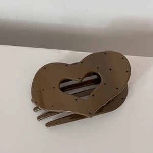Detail of a large heart-shaped brown hair claw clip with classic black polka dots