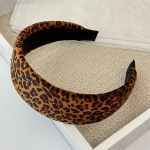 Detailed top view of leopard print wide headband on a textured beige woven tray