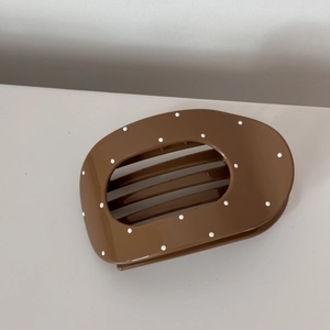 Close-up of minimalist dark brown hair claw clip with white polka dots and glossy finish