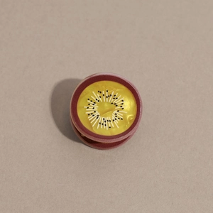 Vue détaillée d'une pince à cheveux ronde kiwi avec fini perlé et texture en acétate de luxe