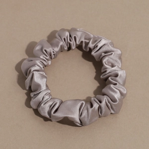 Close-up of champagne satin scrunchie showing glossy texture and soft pleated details