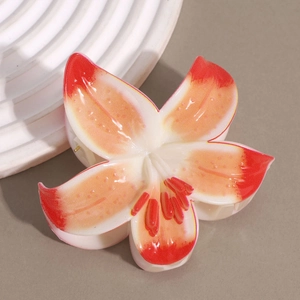 Detailed macro view of an elegant white and orange lily flower hair claw with gradient petals