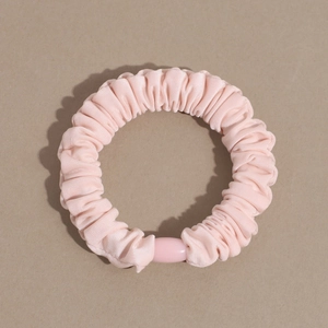 Detail shot of a pink pleated satin scrunchie with a matching oval decorative buckle