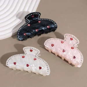Vue détaillée des pinces à cheveux en acétate avec strass cœur en noir, rose et blanc nacré
