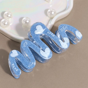 Detail of denim blue acrylic hair claw clip with white heart prints and lucky text