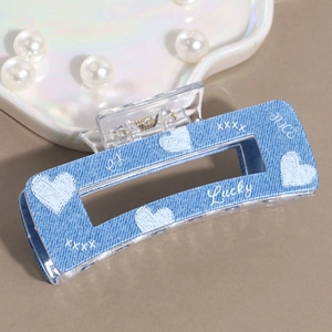 Detail view of denim texture acrylic hair claw clip with heart patterns and lucky text