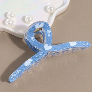 Detail of denim blue hair claw clip with white heart prints and Lucky typography