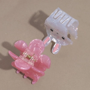 Détail d'une pince à cheveux fleurie rose et d'un clip en acétate lapin mignon