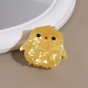 Gros plan d'une pince à cheveux poussin jaune mignonne en acétate texturé élégant