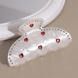 Détail de la pince à cheveux blanche élégante avec strass et pierres précieuses en cœur