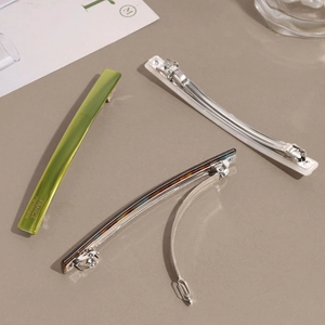 Three-piece acetate hair clip set in green, ivory, and tortoiseshell with gold lettering