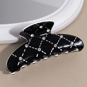 Gros plan sur la pince à cheveux noire élégante avec motif matelassé blanc et strass brillants