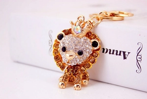 Close-up of golden lion keychain with crown, set with white and amber rhinestones