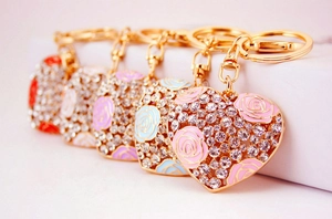 Close-up of heart-shaped alloy keychains with crystal rhinestones and rose flower details