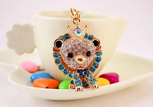 Close-up of golden crown lion keychain with rhinestones on a decorative white dish