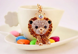 Detailed view of lion keychain with brown rhinestones and crown hanging on a cup