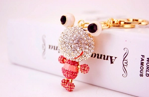 Vue macro d'un porte-clés grenouille orné de strass blancs et roses sur métal doré