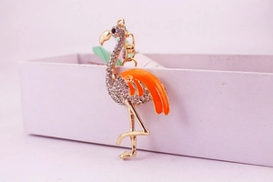 Détail d'un porte-clés flamant rose avec strass blancs et émail orange sur boîte cadeau