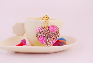 Close-up of gold heart keychain with pink enamel roses and sparkling rhinestones
