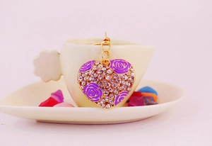 Detail of heart keychain with purple roses and crystals on a golden metal base