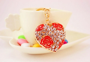 Macro shot of heart-shaped keychain with red rose and crystals on a white porcelain dish