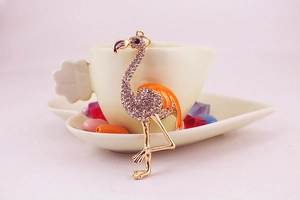Détail du pendentif flamant rose avec diamants blancs étincelants et émail orange vif