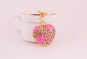 Close-up of heart-shaped keychain with pink roses, sparkling rhinestones and gold alloy finish