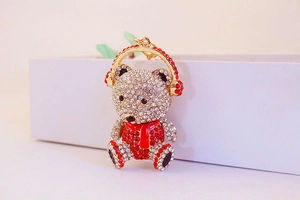 Close-up of a cute teddy bear keychain featuring sparkling rhinestones and red scarf detail