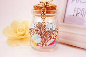 Detail of a heart-shaped keychain with blue enamel rose and sparkling crystals