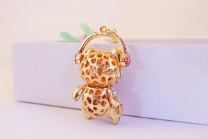 Detailed macro view of a golden bear keychain featuring pink crystal headphones decoration