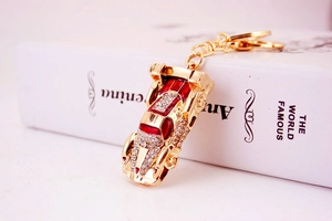 Detail of red enamel car keychain with sparkling white rhinestones and golden chain