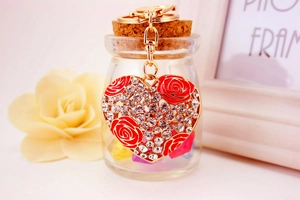 Detailed view of golden heart-shaped keychain with red rose design and sparkling crystals