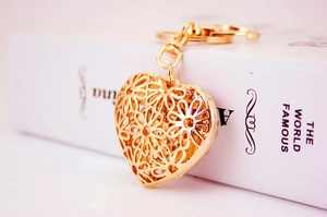 Detailed close-up of golden hollow heart keychain with floral pattern on white book