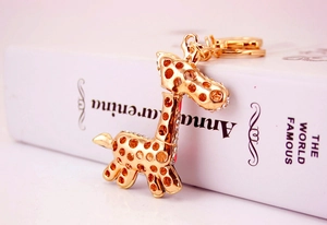 Close-up of golden metal giraffe keychain with white sparkling rhinestones on books