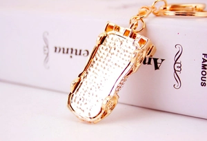 Macro view of a gold-plated car-shaped keychain decorated with sparkling rhinestones