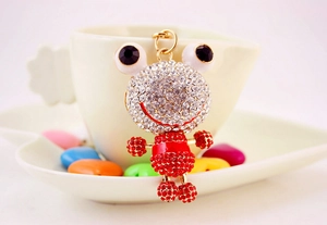 Détail d'un porte-clés grenouille étincelant avec cristaux rouges sur une tasse blanche