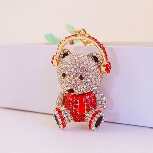 Sparkling crystal teddy bear keychain with headphones and red scarf on golden base