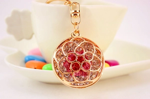 Detail view of rhinestone hollow flower keychain charm hanging on white coffee cup