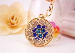 Detailed macro view of a gold hollow flower keychain featuring blue rhinestone embellishments