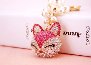 Detail of pink crystal fox keychain with white faux pearls and golden accents