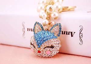 Detailed close-up of a fox-shaped keychain with blue rhinestones and cream pearls