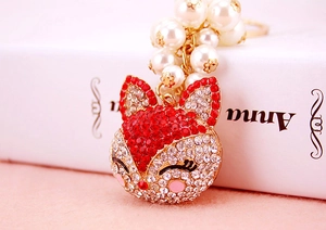 Close-up of fox pendant with red and white rhinestones, pearls and gold key chain